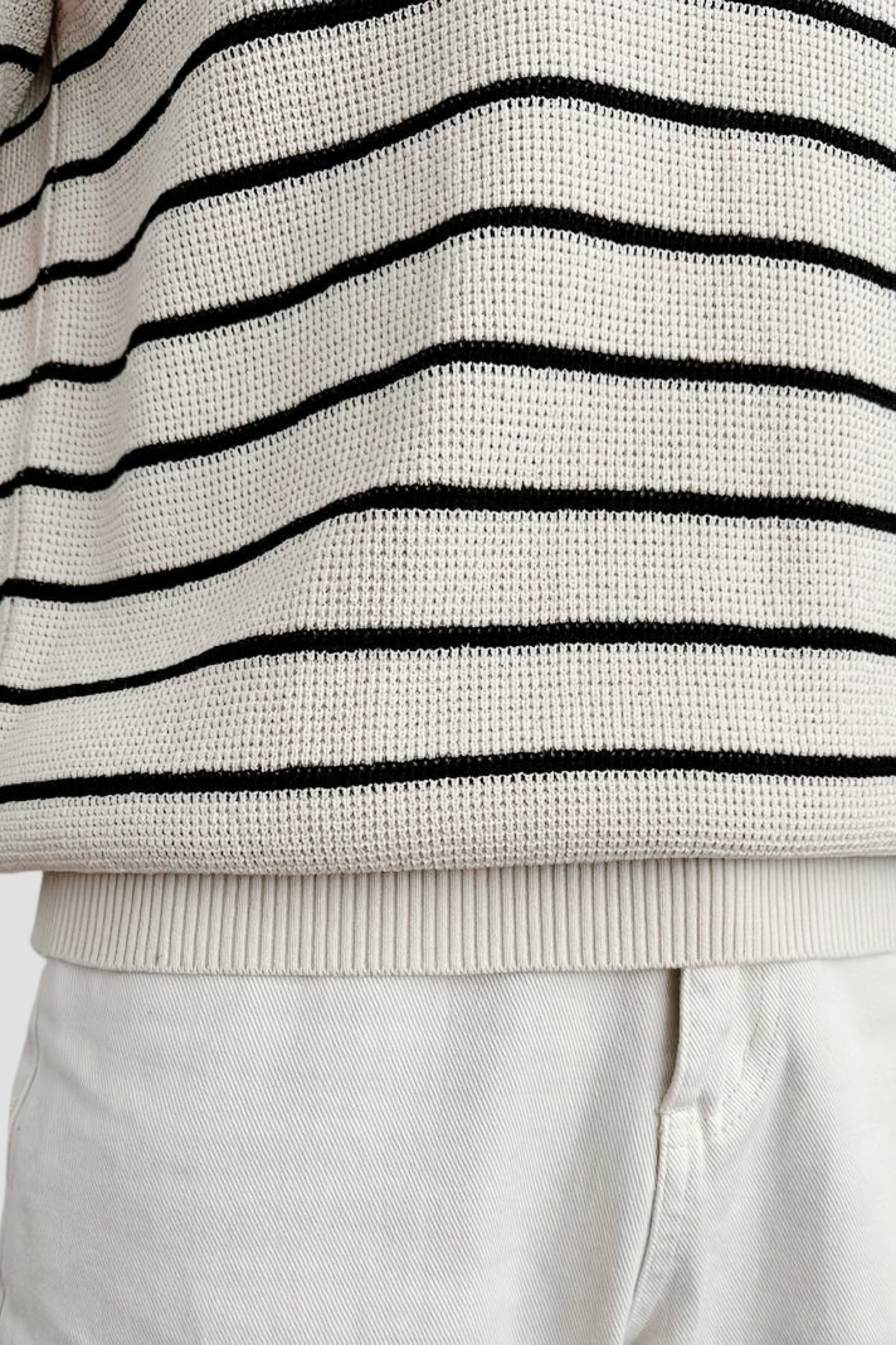 Men's cream-colored polo with horizontal black stripes, featuring an open-collar design and a premium waffle-knit texture.