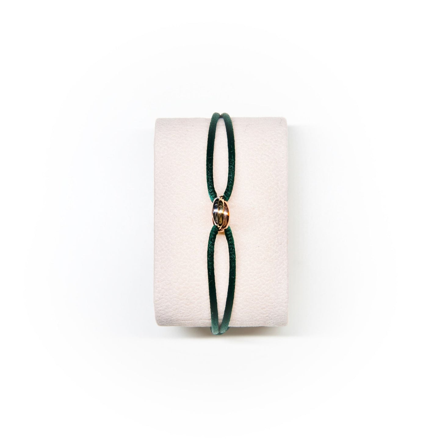 Green bracelet on a white cushion with a white background