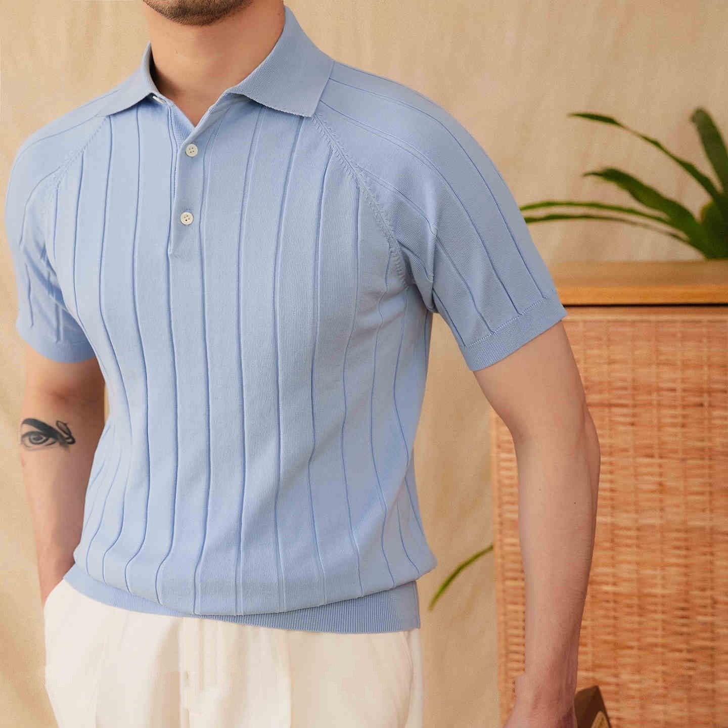 Light blue raglan sleeve polo with a vertical ribbed pattern, styled with cream linen trousers.
