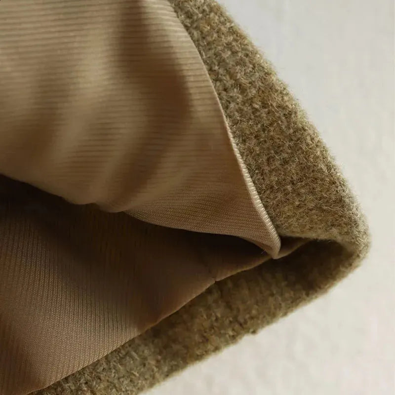 Close-up of a brown cropped textured jacket with gold buttons in a structured boxy fit