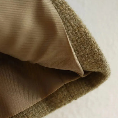 Close-up of a brown cropped textured jacket with gold buttons in a structured boxy fit