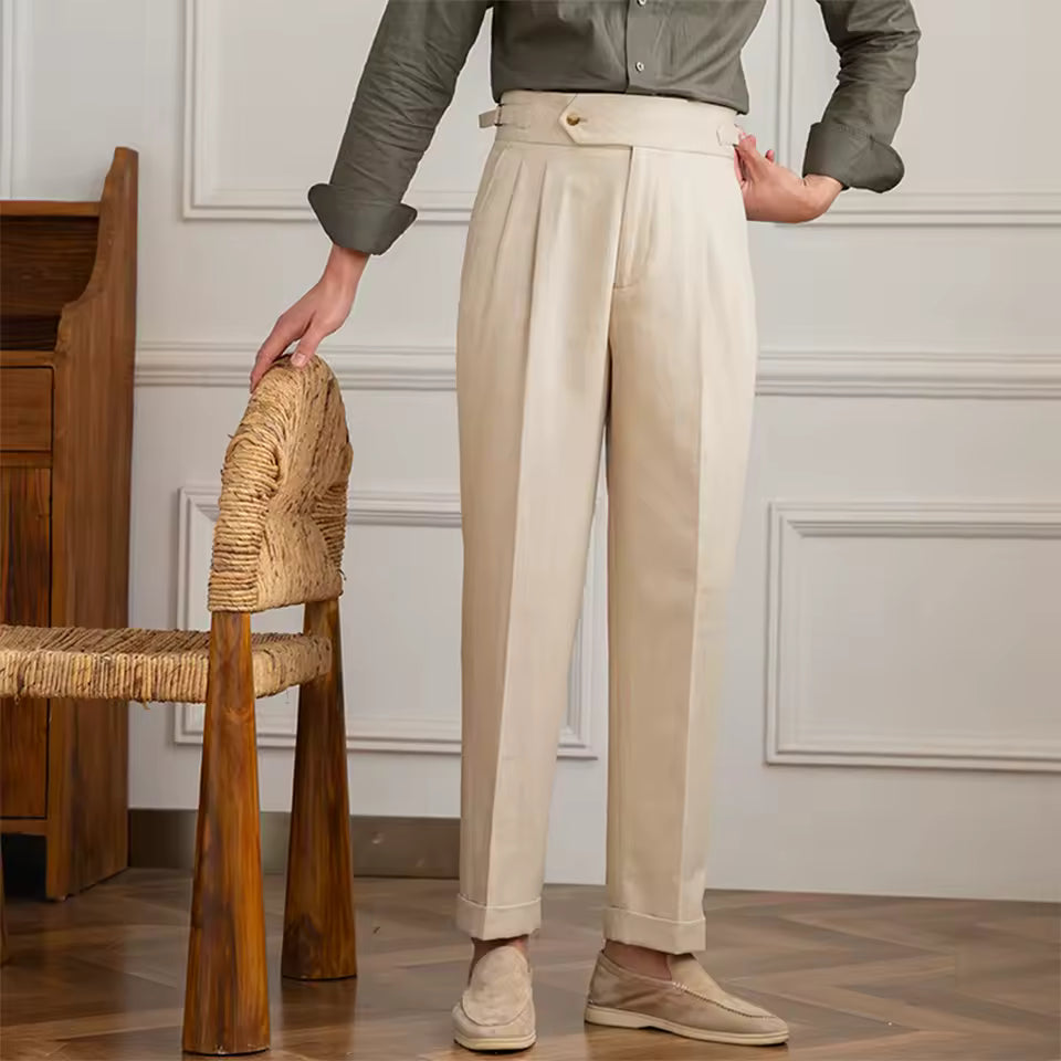 Person wearing beige pants standing next to a wooden chair in an indoor setting.