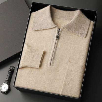Beige sweater with a zipper in a black box, next to a watch on a dark surface.