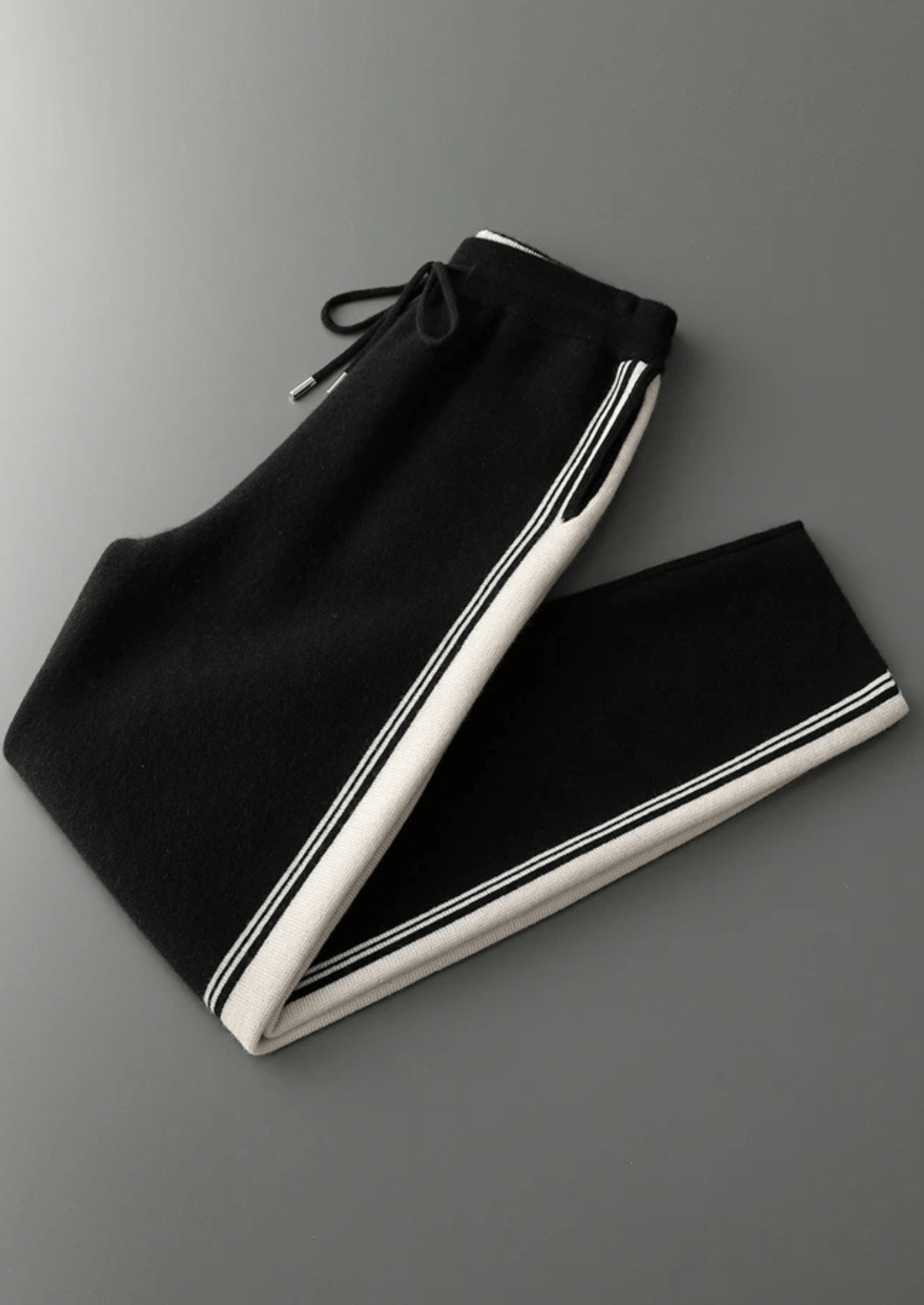 Black pants with white trim on a gray background