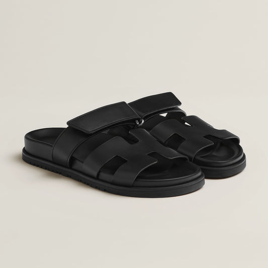 Black sandals with multiple straps on a light gray background