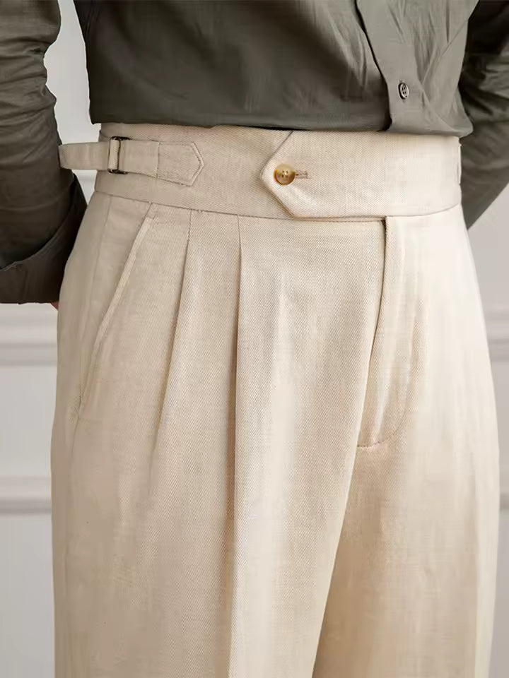 Beige pleated pants with a belt and button on a neutral background
