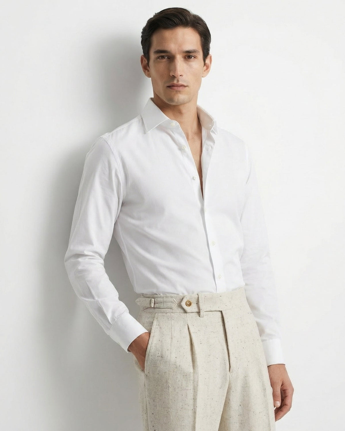Man wearing a white dress shirt and beige pants against a light gray background