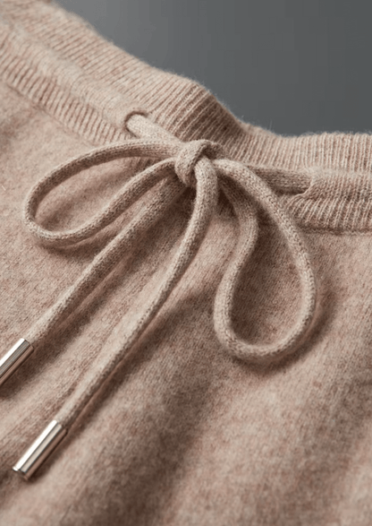 Close-up of a beige knitted sweater with a drawstring detail.