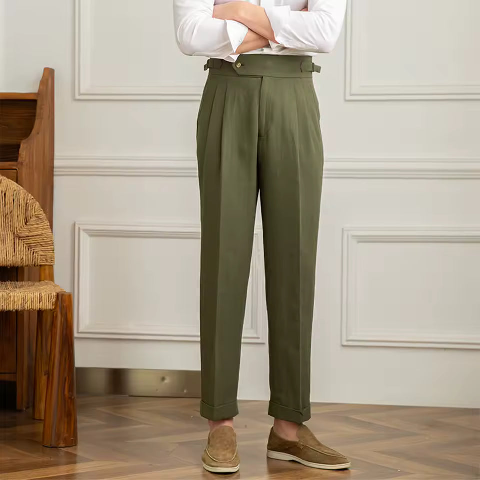 Person wearing olive green pants and a white shirt in a room with wooden floor and white walls.