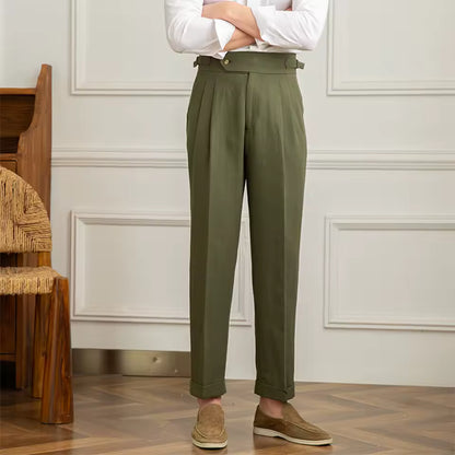 Person wearing olive green pants and a white shirt in a room with wooden floor and white walls.