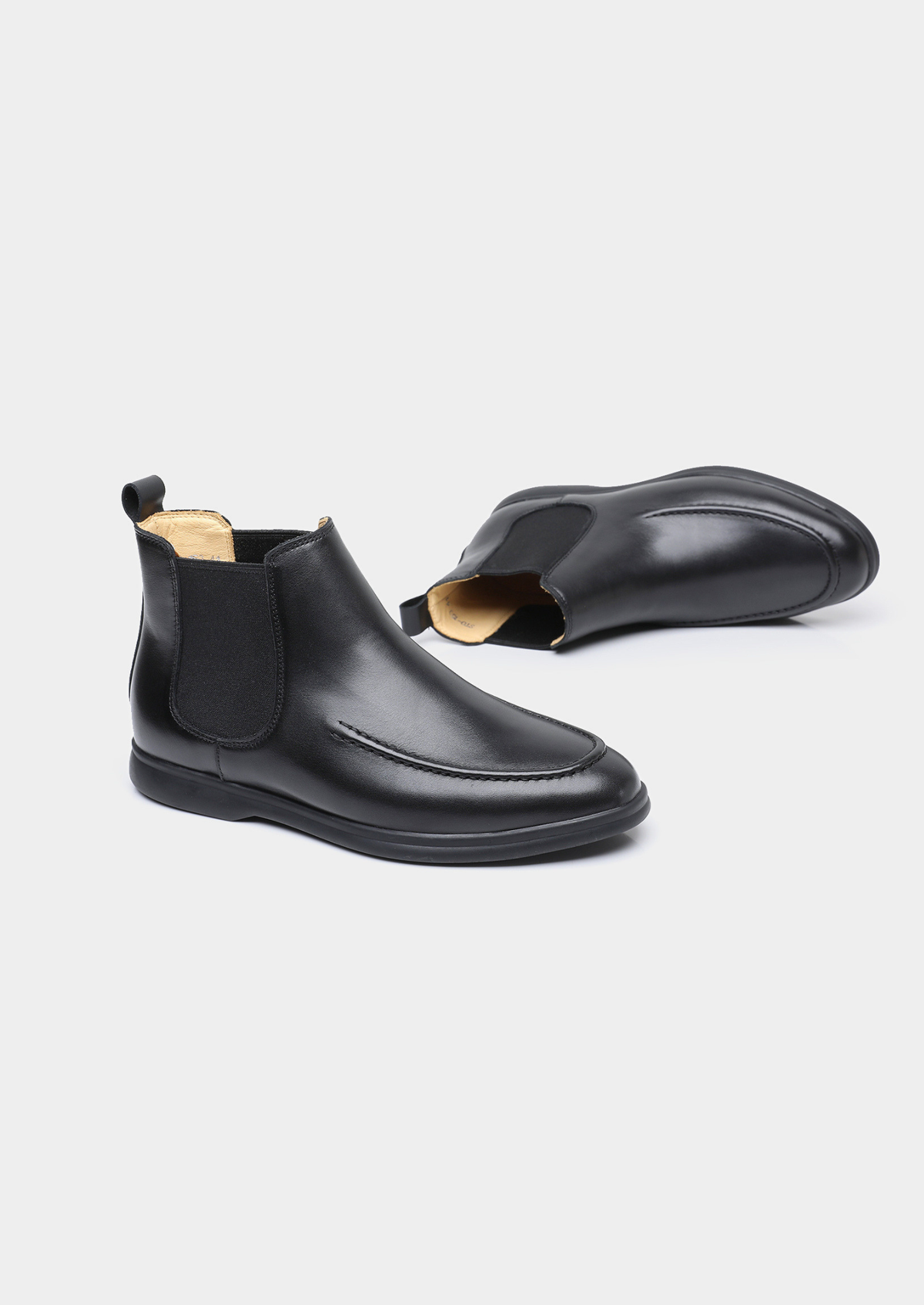 Pair of men smooth black leather Chelsea boots with moccasin apron toe stitching and black rubber sole
