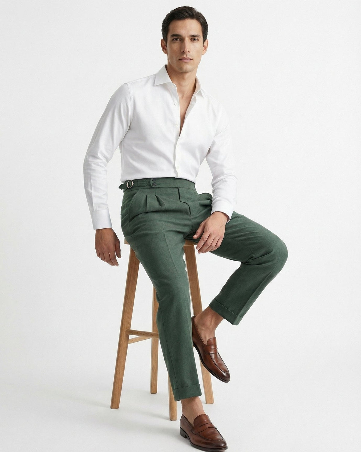 Men's forest green double-pleated cotton blend trousers showing extended crossover button waistband and side buckle