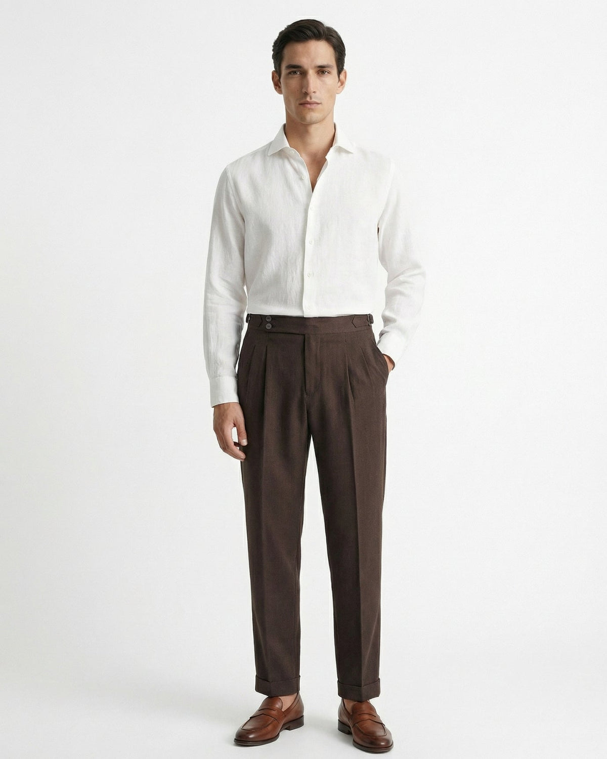 Men's brown double-pleated cotton blend trousers showing extended crossover button waistband and side buckle