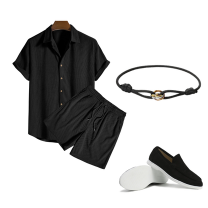 Black shirt and pants set with a bracelet and loafers on a white background