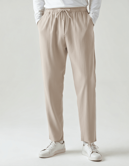 Men's beige relaxed linen pants featuring a comfortable elasticated drawstring waist and a tailored straight-leg silhouette.