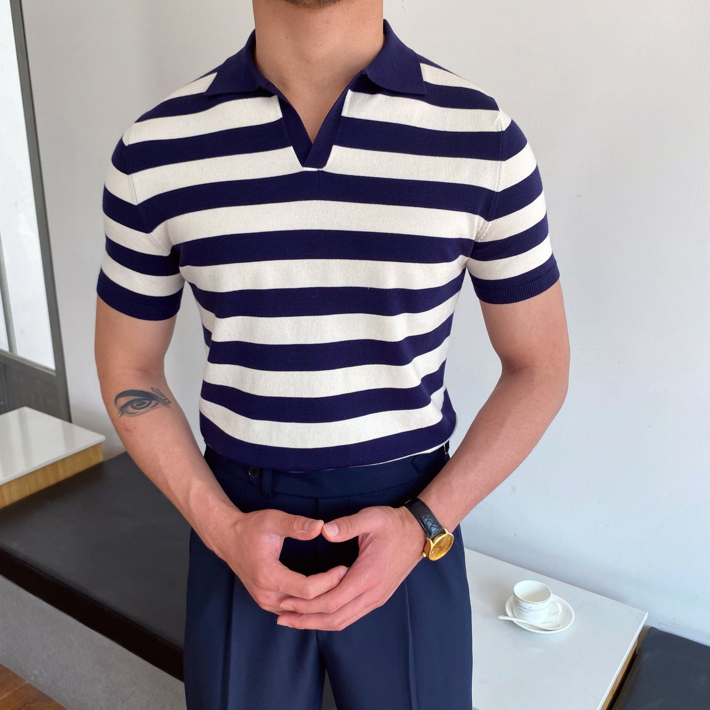 Person wearing a navy and white striped polo shirt in an indoor setting.