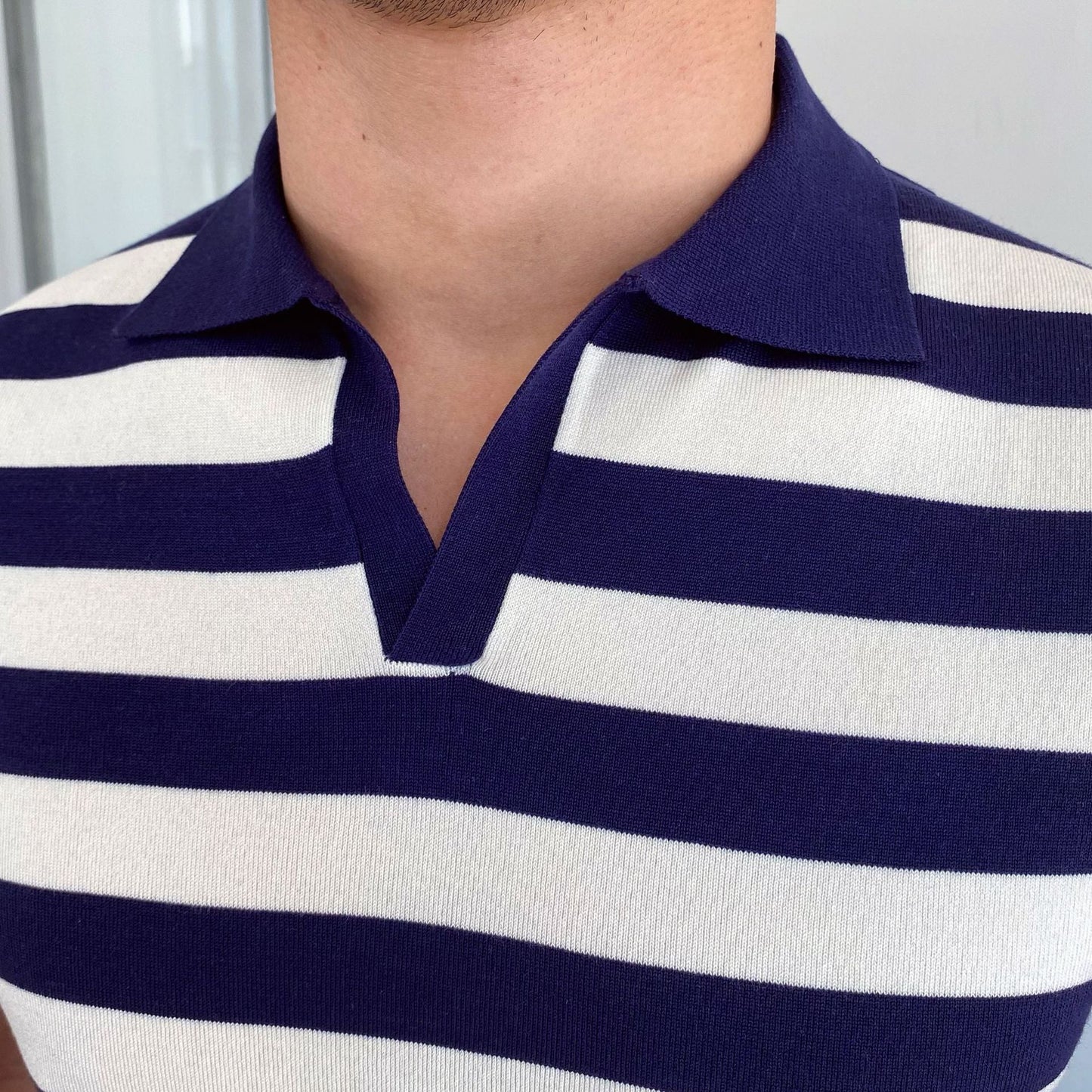 Men's navy and white horizontal Breton striped polo featuring a seamless open-collar design and a tailored slim fit.