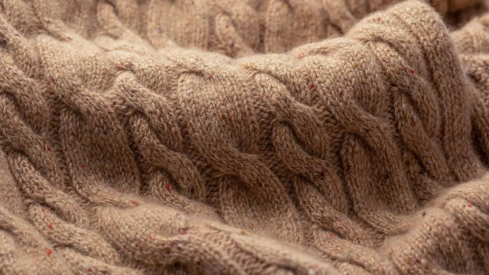 Close-up of cable-knit fabric in beige.