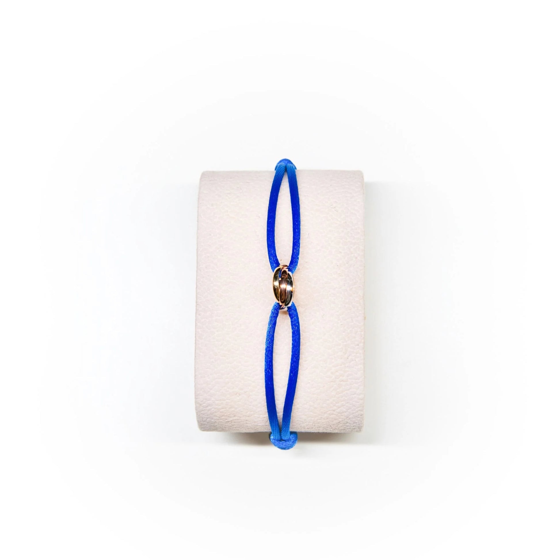 Blue bracelet on a white cylindrical stand with a white background