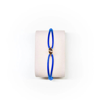 Blue bracelet on a white cylindrical stand with a white background