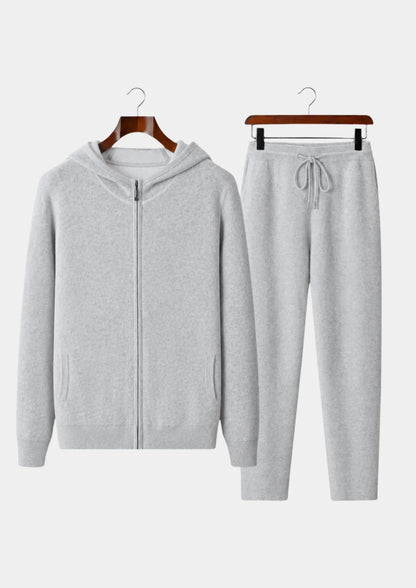 Men's grey 100% cashmere set featuring a full-zip hoodie with silver hardware and matching tapered knit pants with a drawstring waist.