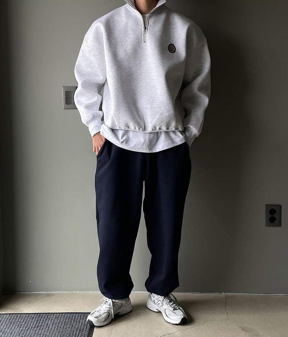Men's gray high-neck quarter-zip sweatshirt featuring a loose fit, dropped shoulders, and a structured collar.