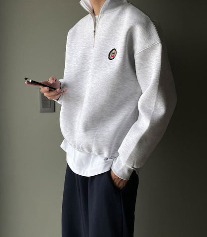 Men's gray high-neck quarter-zip sweatshirt featuring a loose fit, dropped shoulders, and a structured collar.