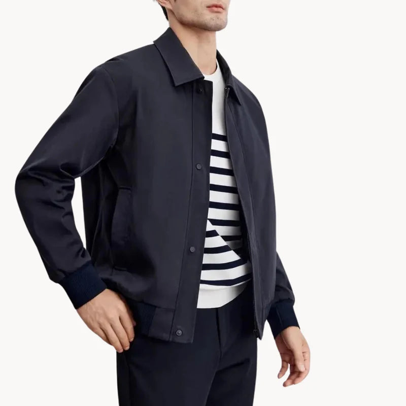 Man wearing a navy jacket over a striped shirt on a white background