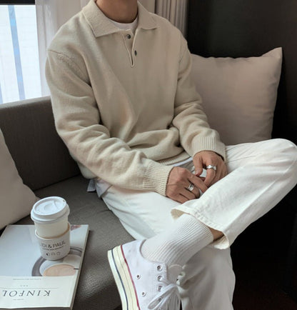 Men's ivory loose-fit buttoned knit polo sweater featuring a smooth cotton-blend and drop-shoulder silhouette.