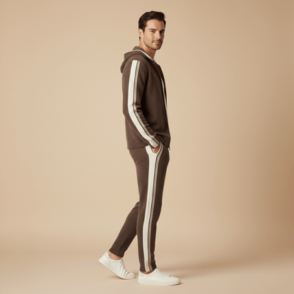 Man wearing a brown tracksuit with white stripes on a beige background