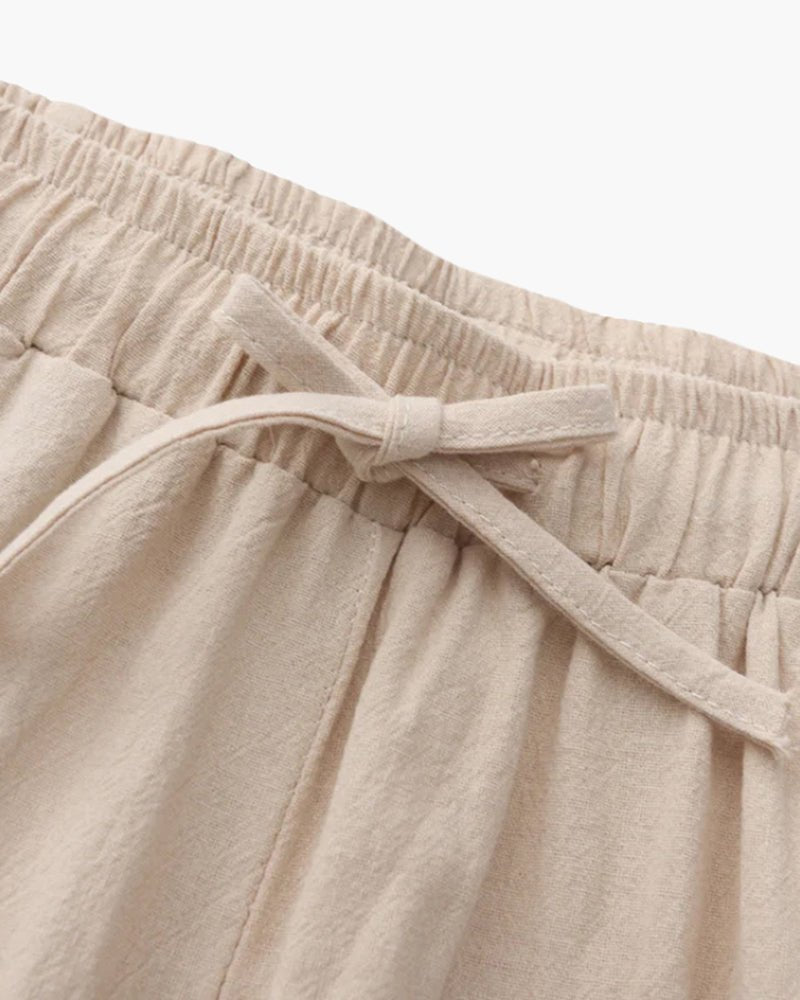 Close-up of beige linen pants with an elastic waistband on a light background
