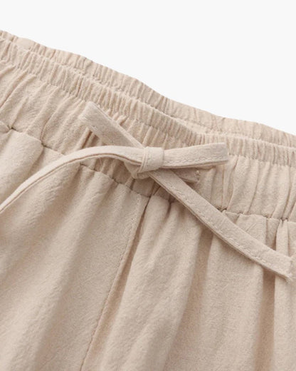 Close-up of beige linen pants with an elastic waistband on a light background