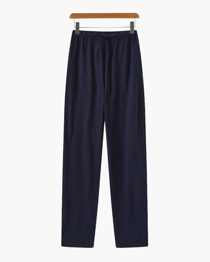 Men's navy blue straight-leg linen pants with a refined architectural drape and functional side pockets.