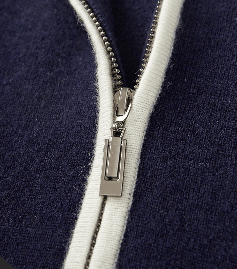 Close-up of the silver-tone metal zipper and white contrast piping on the navy merino wool polo cardigan.