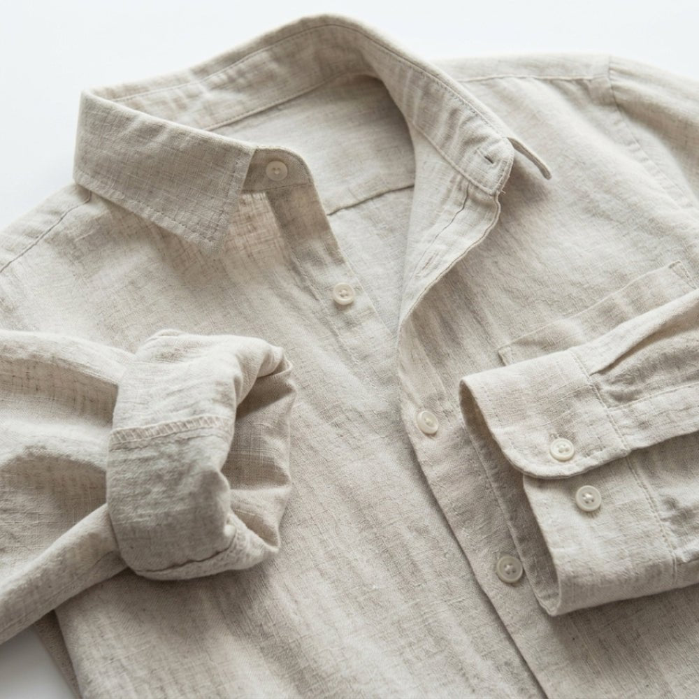 Light beige linen shirt with rolled-up sleeve on a white background