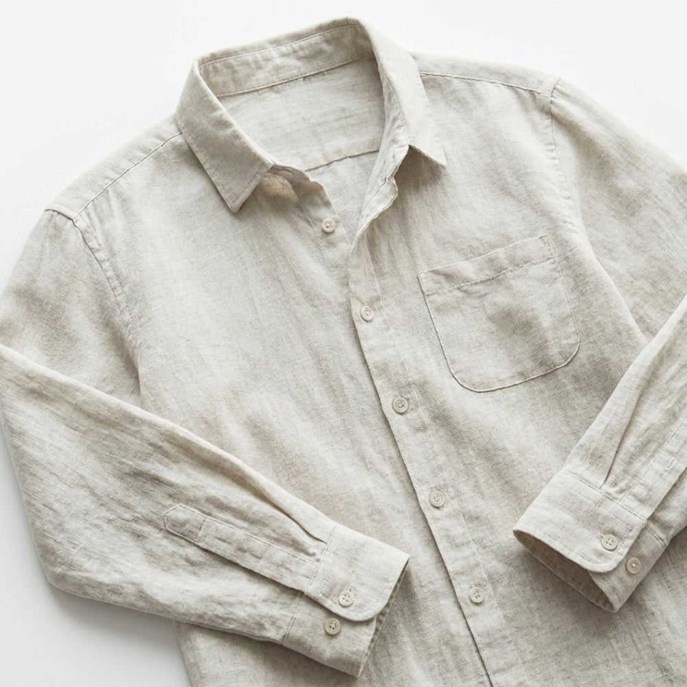 Light beige linen shirt with rolled-up sleeves on a white background