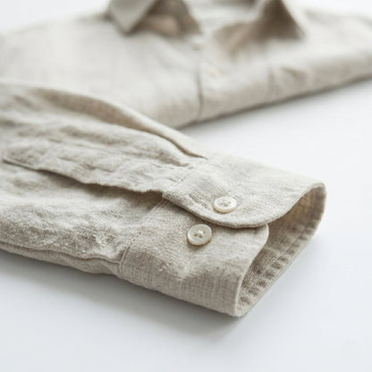 Folded beige linen shirt on a white surface