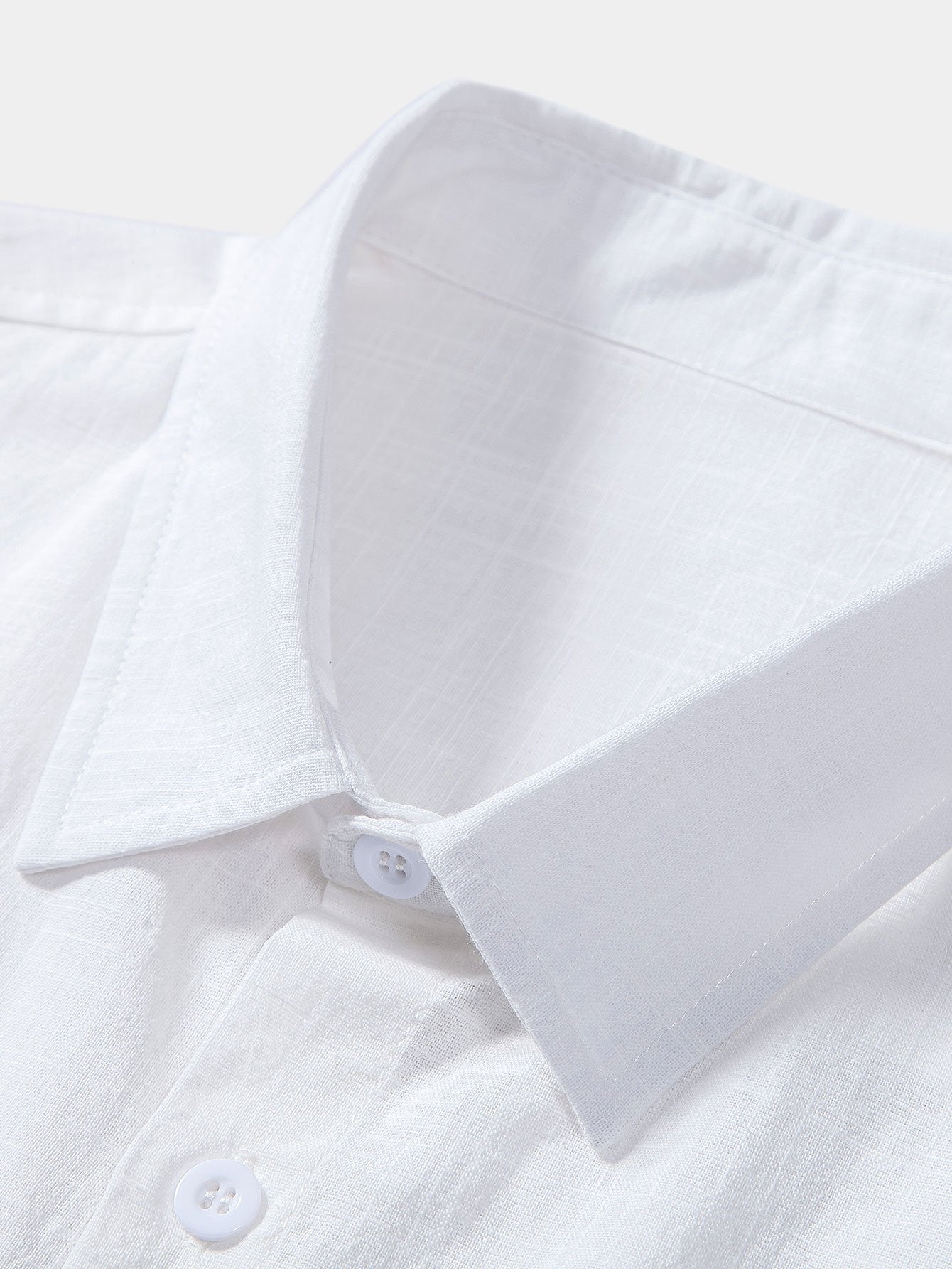 Close-up of a white shirt with a collar and buttons on a light background