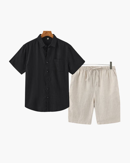 Men's black short-sleeved linen shirt paired with beige tailored linen shorts for a refined Mediterranean style.