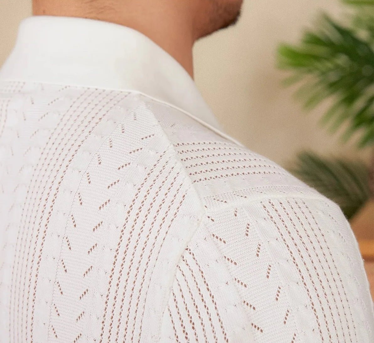 Men's white Pointelle knit polo featuring a sophisticated geometric open-stitch pattern and a classic buttoned neckline.