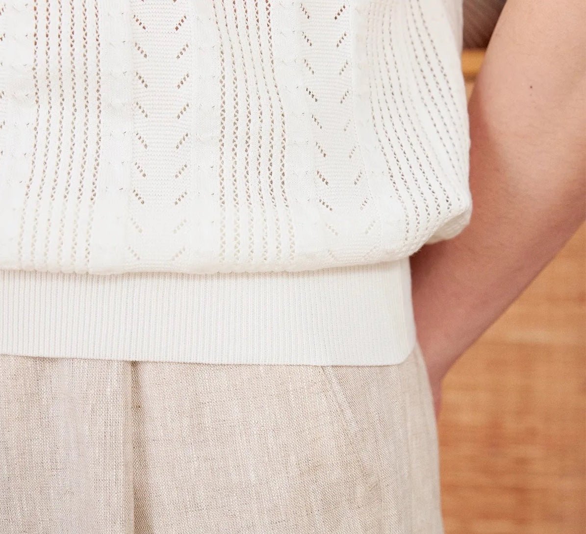 Men's white Pointelle knit polo featuring a sophisticated geometric open-stitch pattern and a classic buttoned neckline.