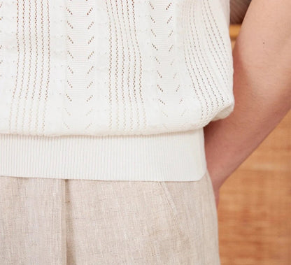 Men's white Pointelle knit polo featuring a sophisticated geometric open-stitch pattern and a classic buttoned neckline.