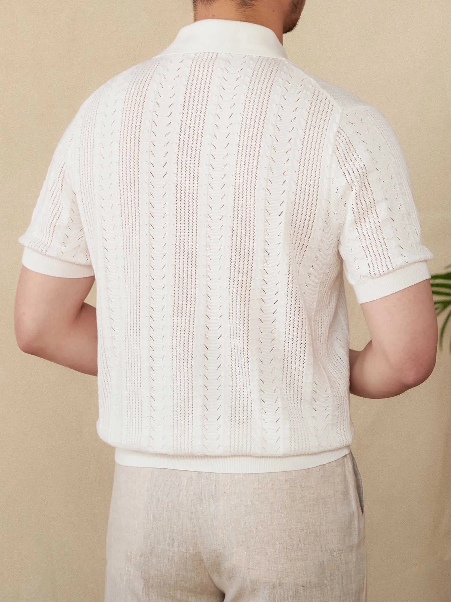 Men's white Pointelle knit polo featuring a sophisticated geometric open-stitch pattern and a classic buttoned neckline.