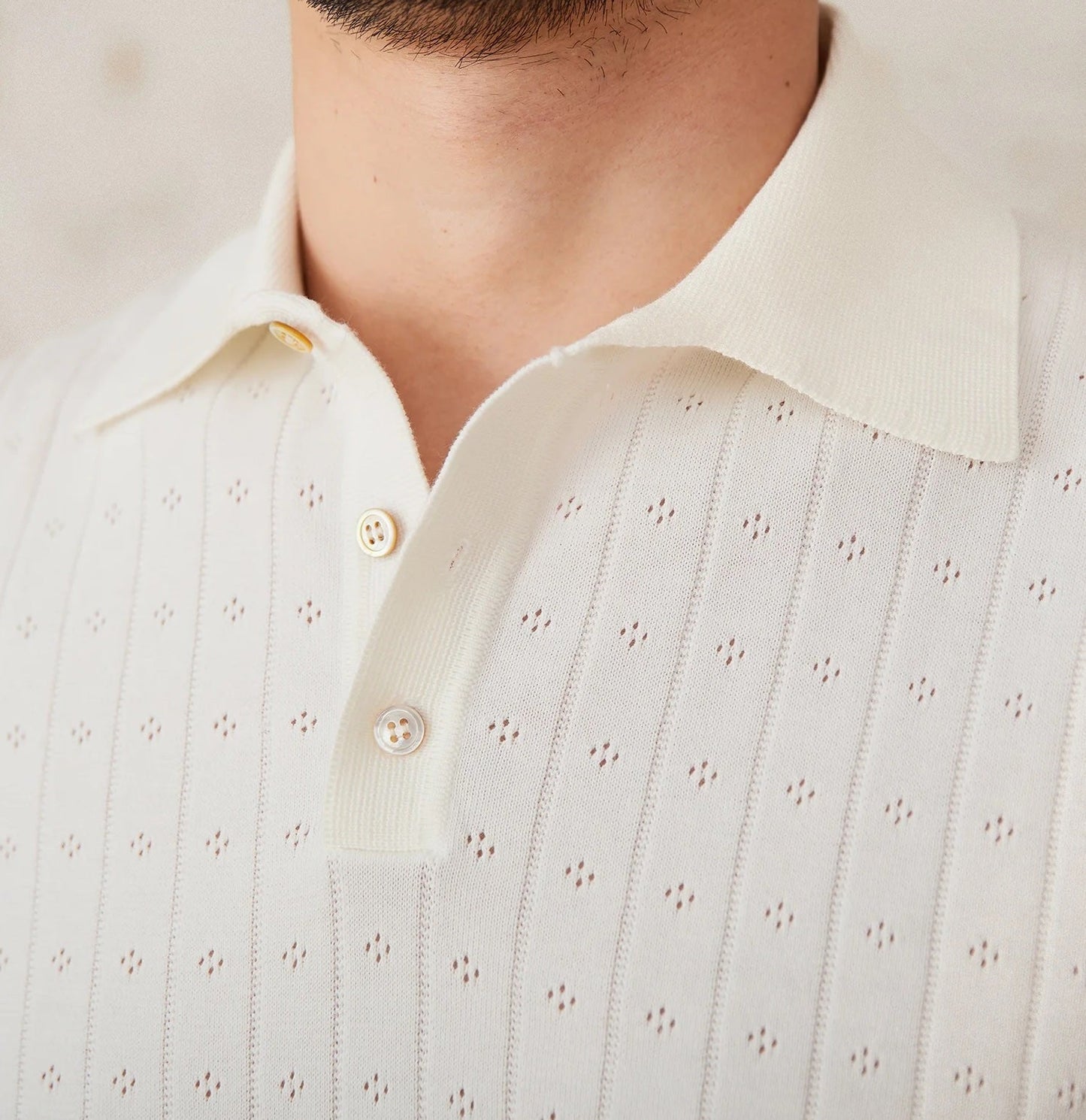 Men's crisp white 100% cotton polo featuring an intricate pointelle vertical ribbed texture and a refined buttoned placket.
