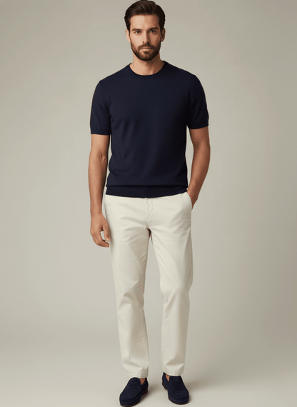 Man wearing a navy premium cashmere crewneck t-shirt and white pants against a plain background
