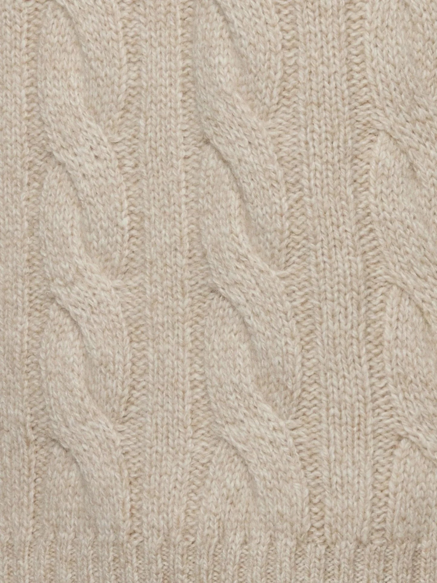 Close-up of beige knitted fabric with cable pattern
