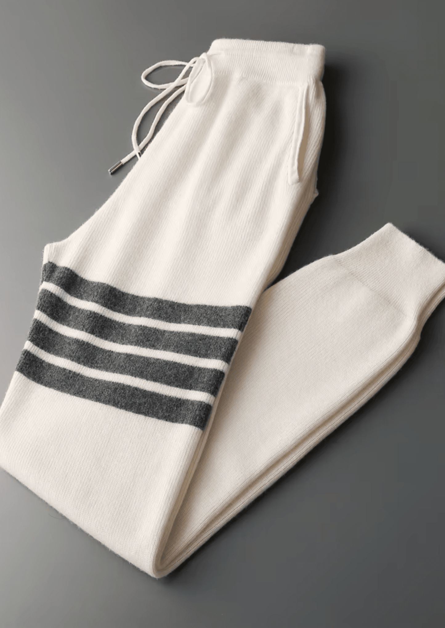 Elegant ivory white Merino wool tracksuit featuring a soft-touch knit hoodie and matching tailored joggers with tonal stripes.