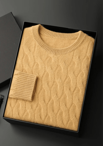 Beige cable knit sweater in a black box on a dark background