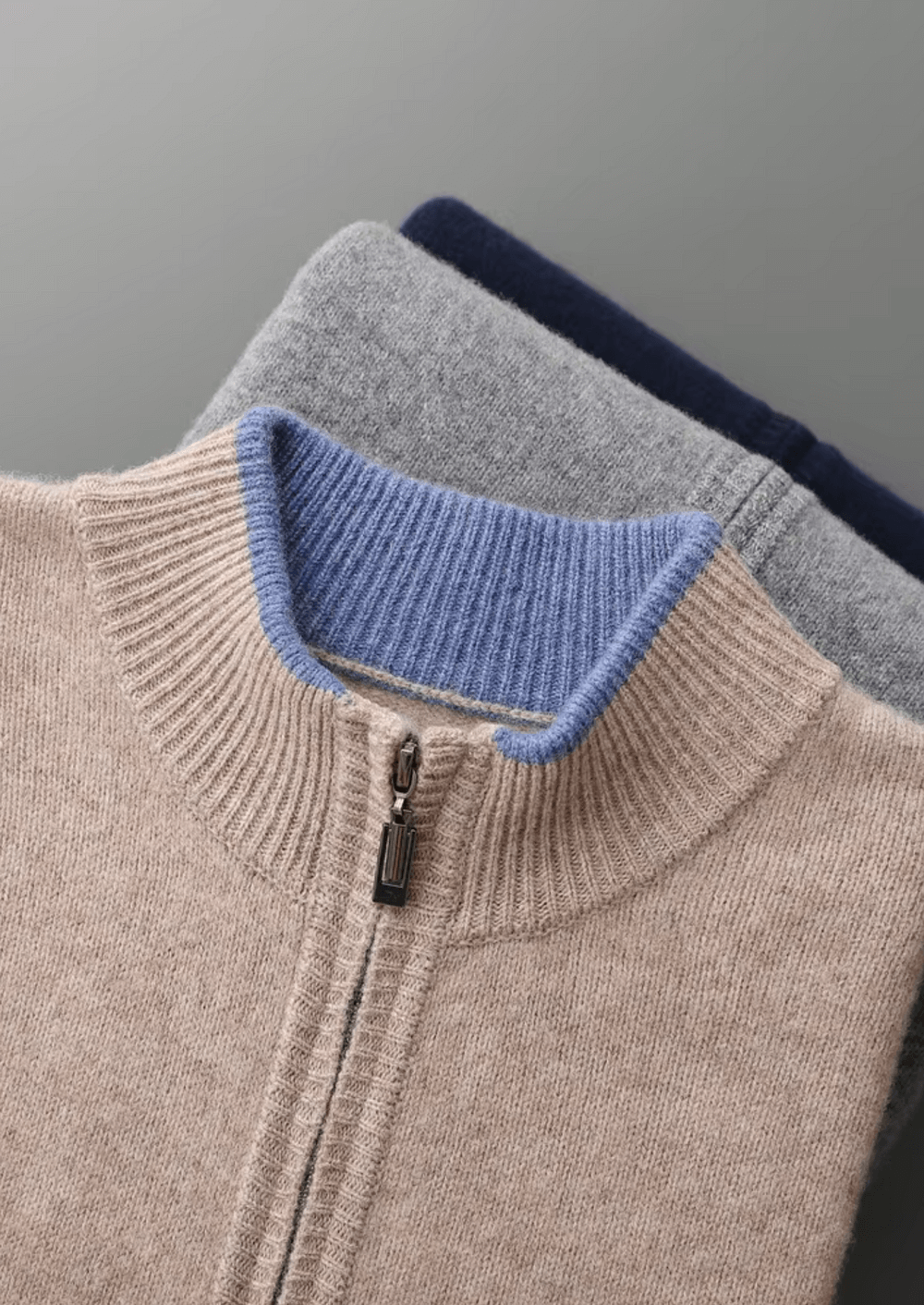 Close-up of a sweater with a blue collar and gray sleeves on a gray background