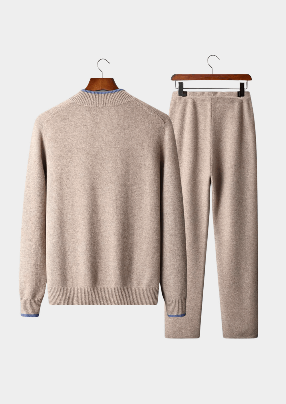 Beige sweater and pants set on hangers against a white background